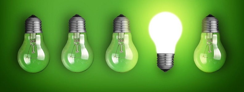 row of green light bulbs sitting next to each other on a green background. One of the light bulbs is glowing.