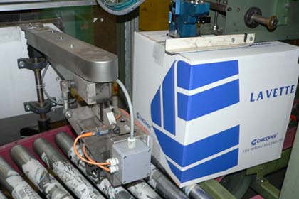 The Padlocker auto case sealer closes the product boxes with tape. Immediately after this, a robotic arm comes into action to glue a barcode label on the box