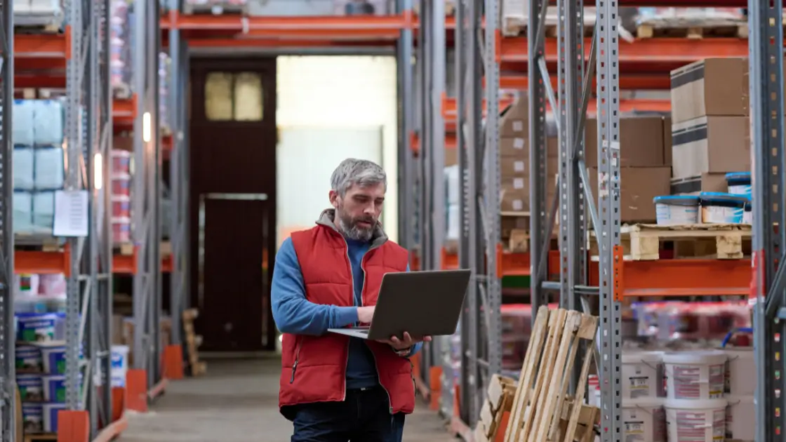 man holding a laptop in a distribution centre