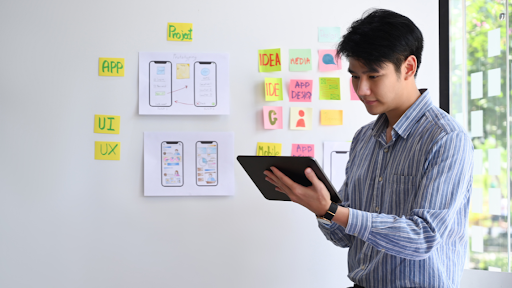 A young man standing focused on testing mobile applications.